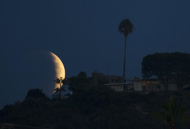 A blood red moon rises behind a hilltop residence in Solana Beach